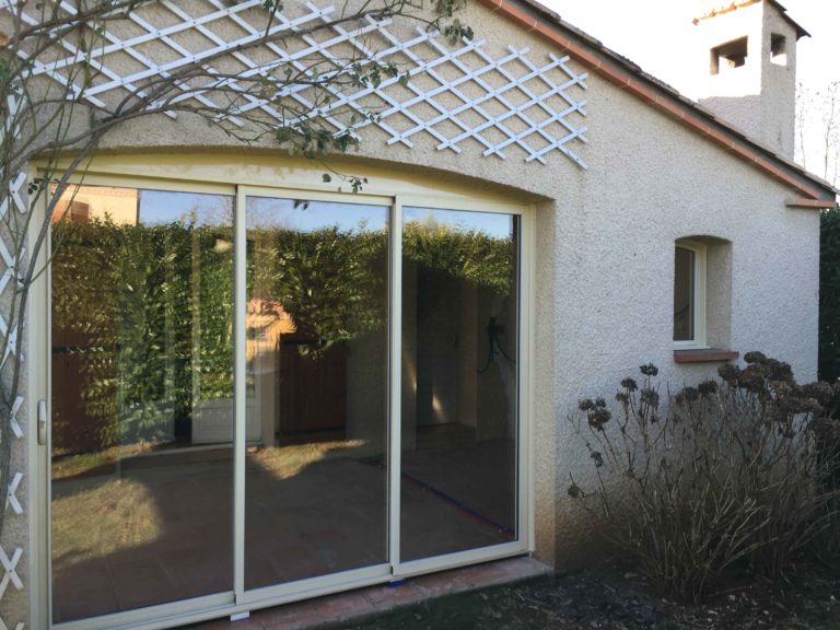 Baie coulissante blanche sous une pergola en bois