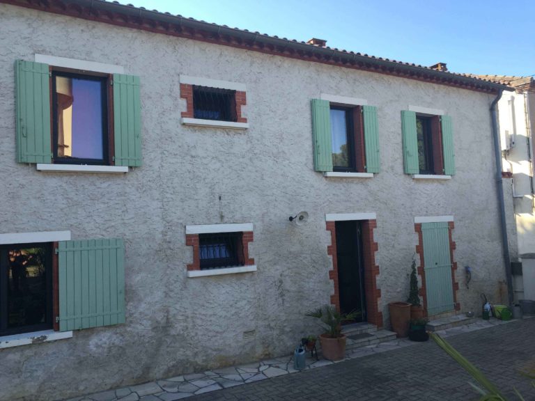 Façade en pierre avec fenêtres et volets vert d'eau