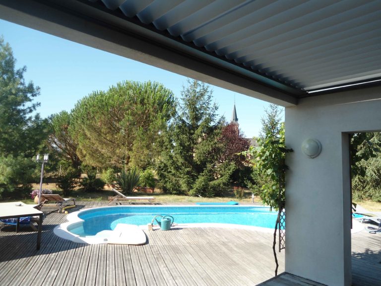 Vue sur la piscine depuis une terrasse sous pergola