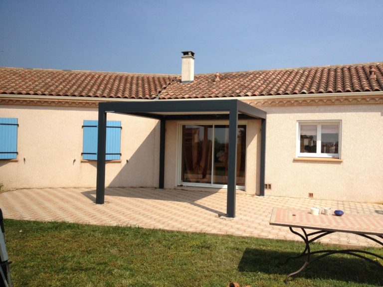 Pergola bioclimatique anthracite devant une façade à volets bleus