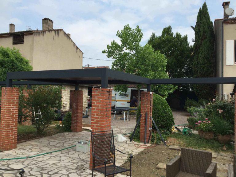 Pergola anthracite sur colonnes en brique, cour pavée