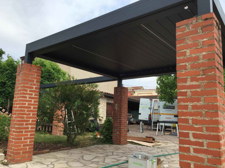 Pergola bioclimatique posée entre des piliers en brique