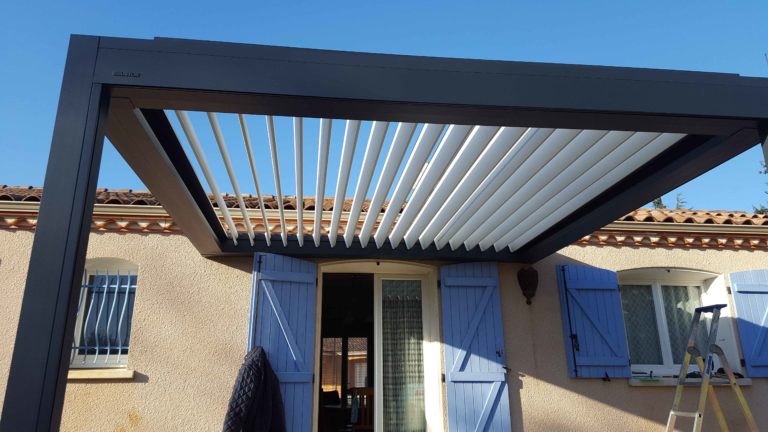 Pergola bioclimatique anthracite en contre-plongée, lames ouvertes