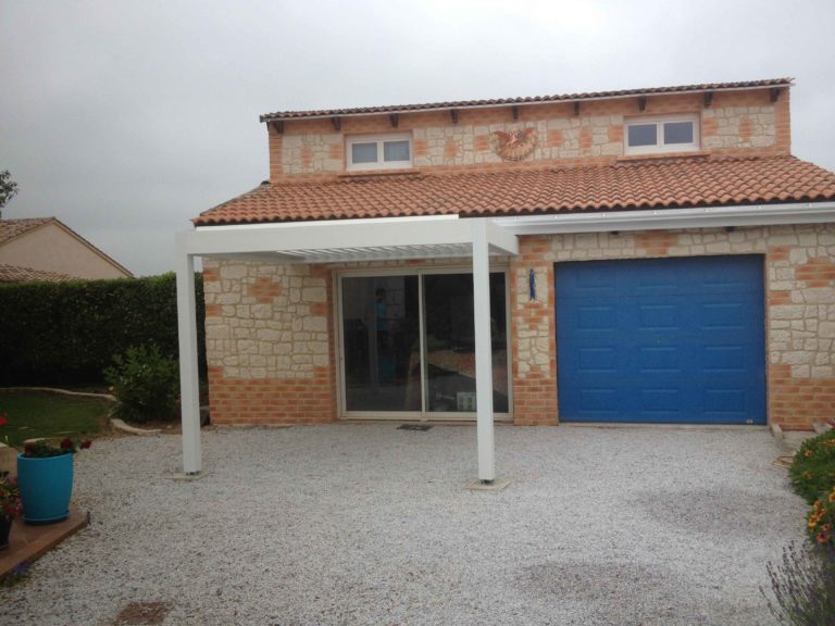 Porte de garage bleue et pergola blanche sur une maison de plain-pied