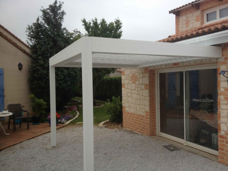 Pergola blanche adossée à une façade en pierre