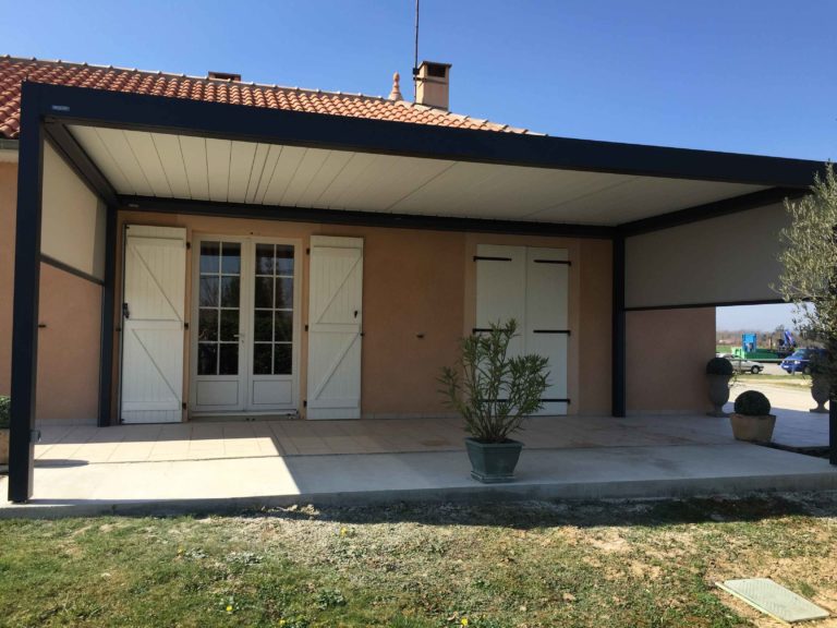 Grande pergola anthracite le long d'une façade à volets blancs