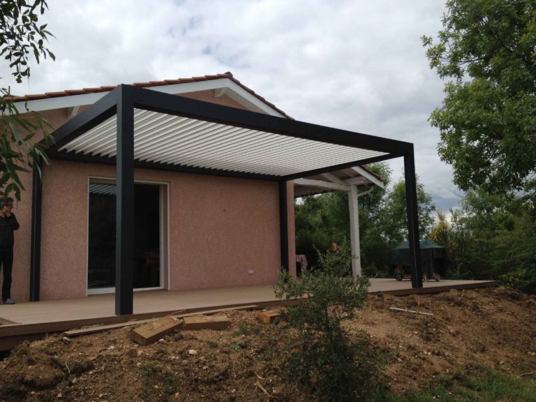 Pergola à lames orientables anthracite contre une façade rose