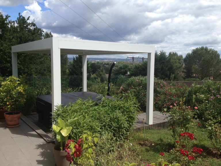 Pergola blanche autoportante dans un jardin arboré