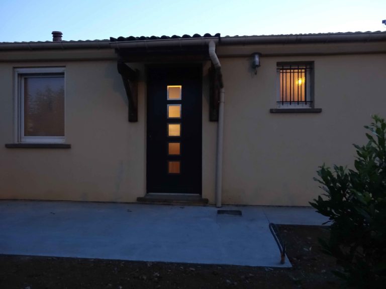 Porte d'entrée sombre à vitrages sur une maison de plain-pied