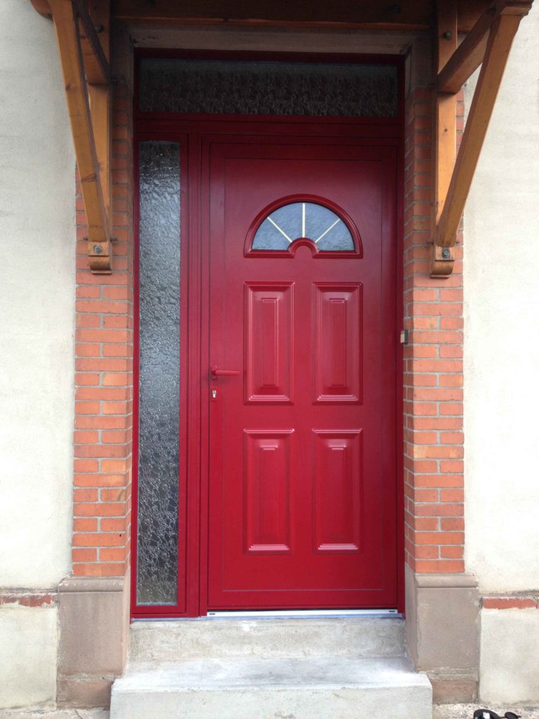 Porte d'entrée rouge à oculus sous auvent
