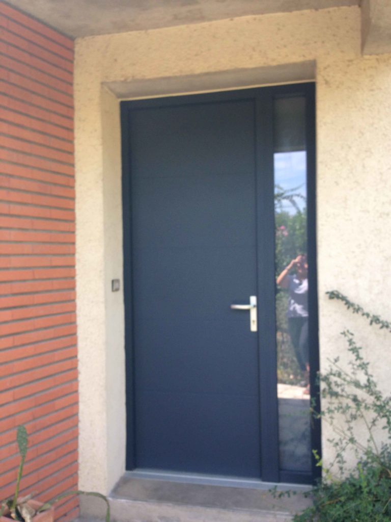 Porte d'entrée anthracite à inserts sur façade en brique et enduit