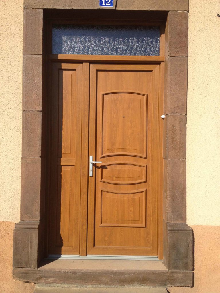Porte d'entrée en bois mouluré dans un encadrement en pierre