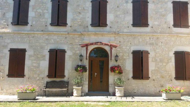 Porte d'entrée en bois cintrée sur façade en pierre