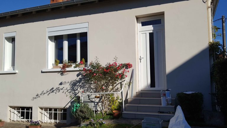 Porte d'entrée blanche sur maison enduite et rosiers