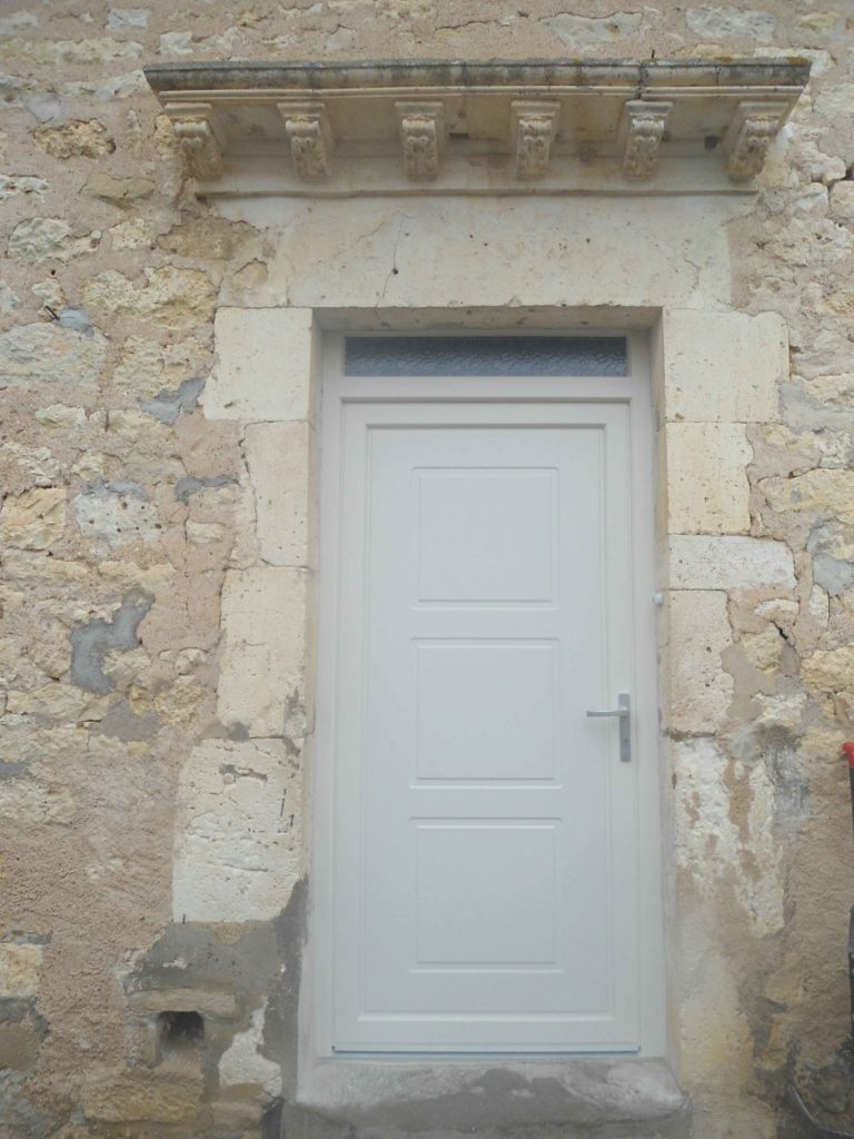 Porte d'entrée blanche dans un encadrement en pierre