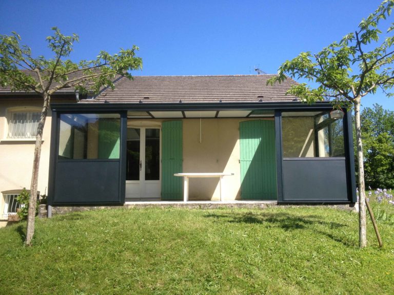 Terrasse couverte devant une maison aux volets verts