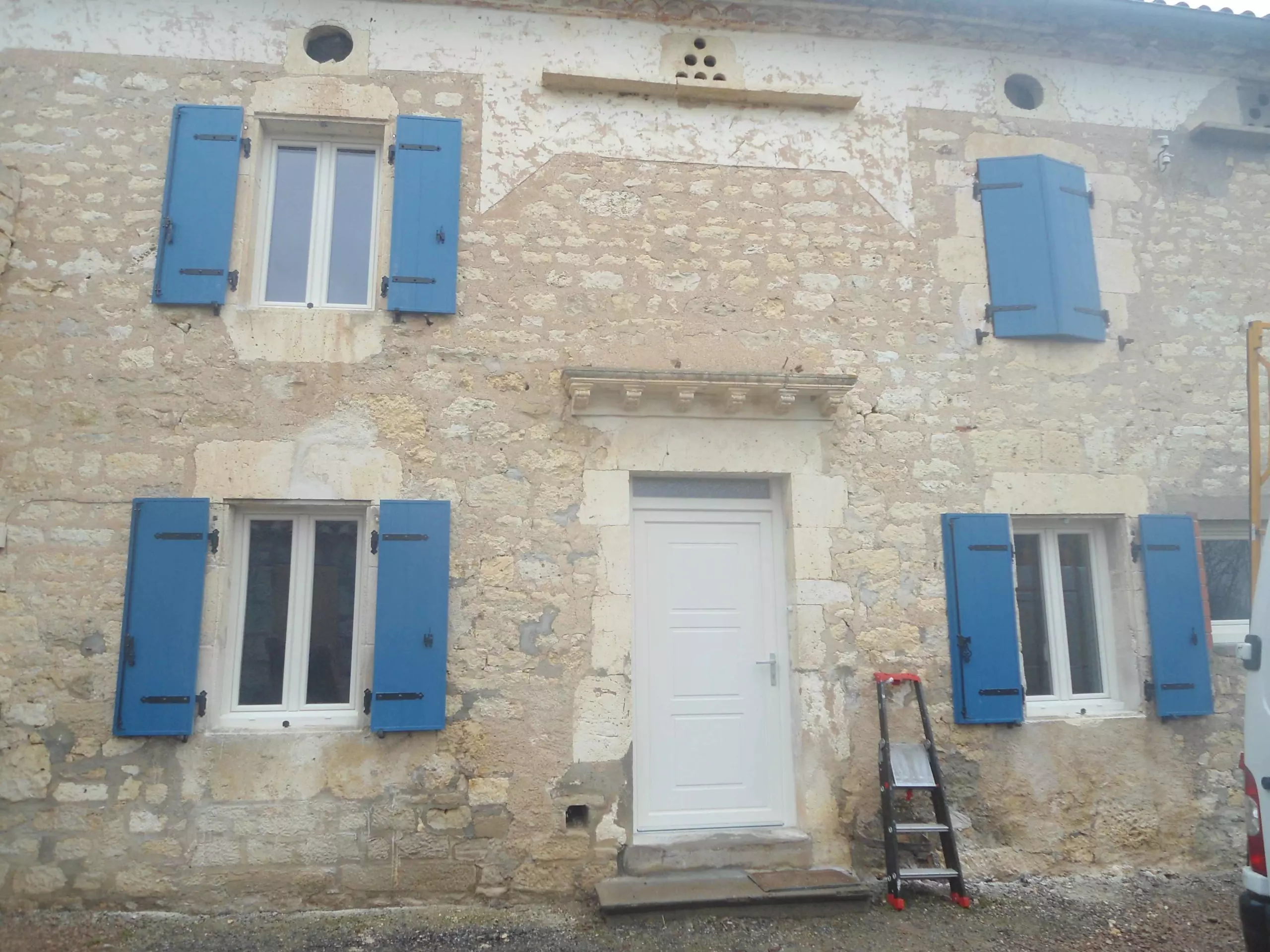 Volets battants bleus posés par EXTEND sur une maison en pierre