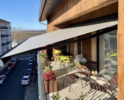 Store banne B25 ouvert, offrant de l'ombre sur un balcon.