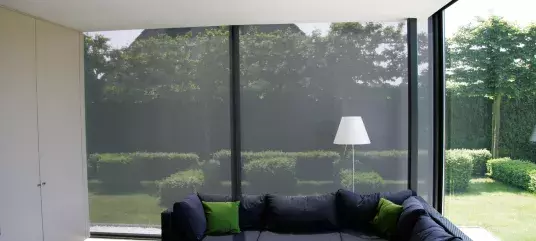 Store intérieur tamisant dans un salon moderne avec baie vitrée donnant sur un jardin verdoyant.