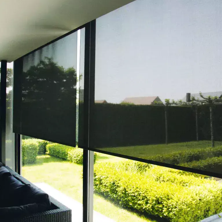 Store intérieur tamisant baissé sur de grandes baies vitrées avec vue sur un jardin lumineux.