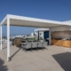 Terrasse moderne avec pergola adossée, cuisine extérieure et salle à manger en plein air.
