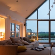 Salon moderne lumineux avec de grandes baies vitrées offrant une vue panoramique sur la campagne.