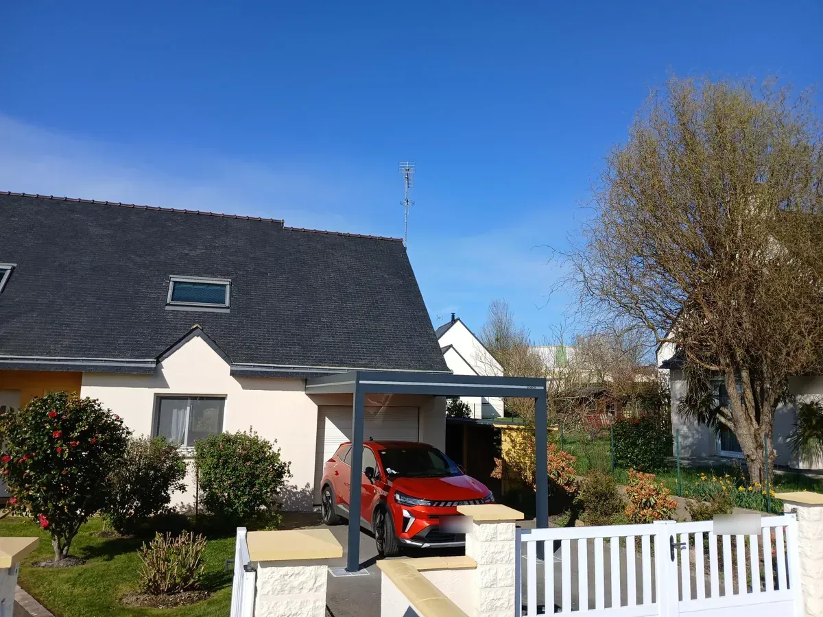Carport aluminium indépendant dans un jardin, une voiture rouge garée dessous