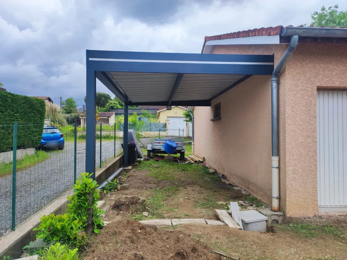 Carport aluminium adossé à toit en bac acier le long d’une maison