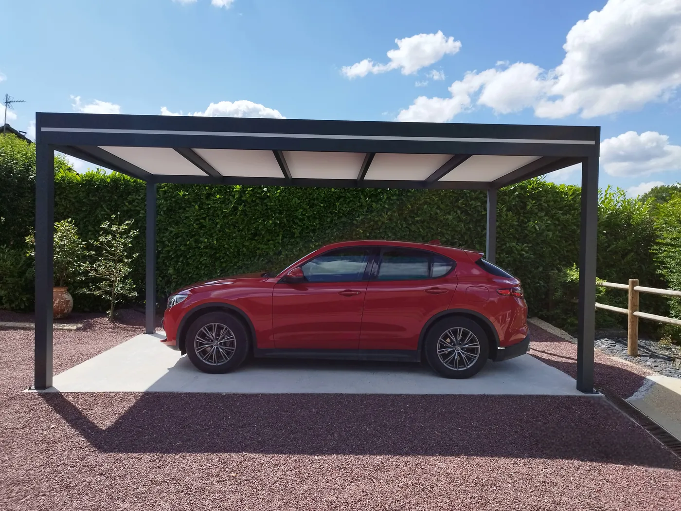 Carport aluminium haut et dégagé, une voiture rouge garée dessous