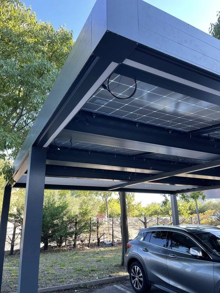 Vue de dessous d’un carport solaire : panneaux photovoltaïques sur une structure aluminium, voiture garée