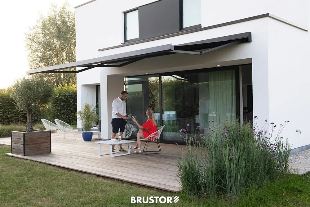 Store banne Brustor sur une terrasse en bois devant une maison contemporaine