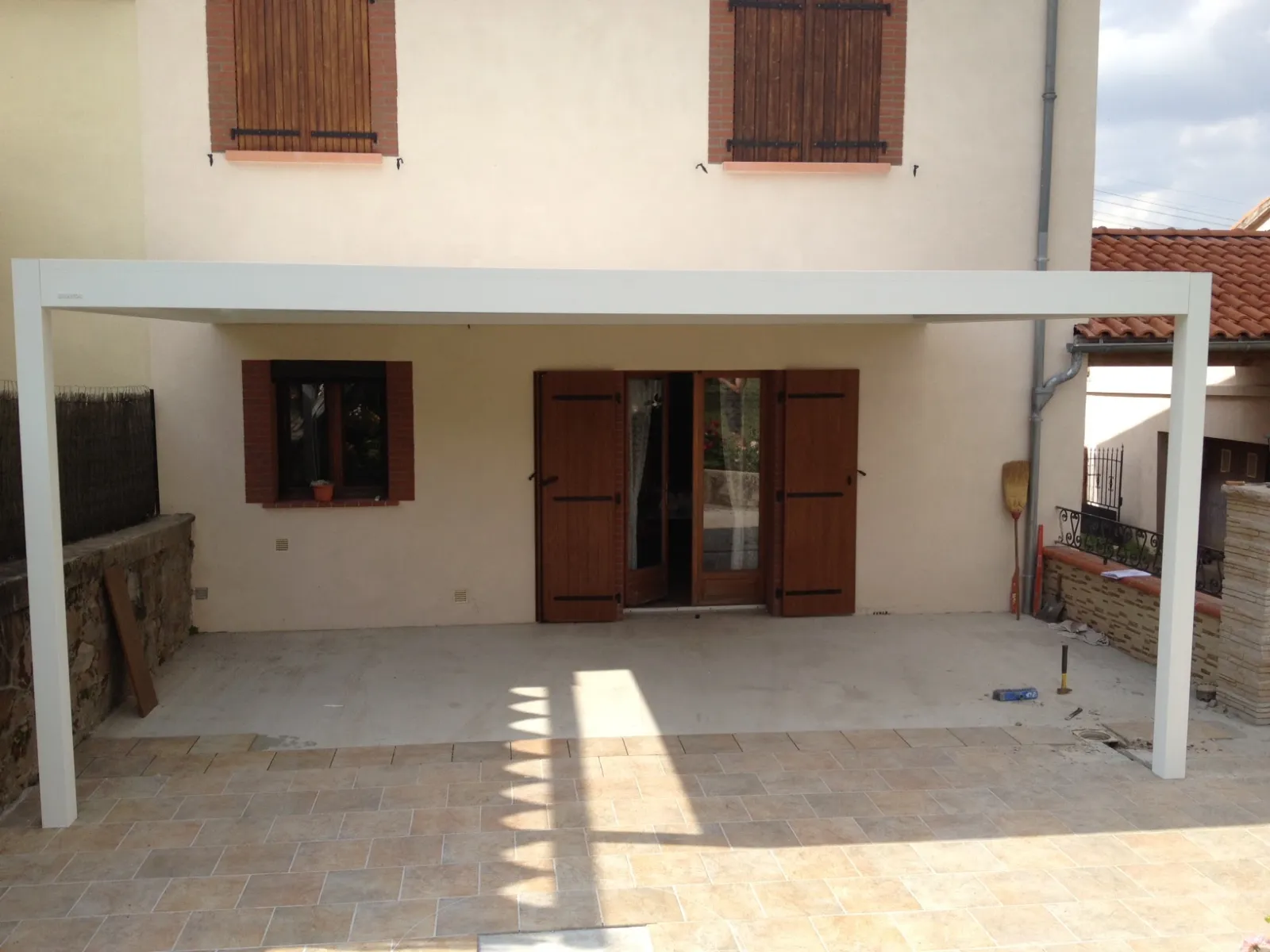 Pergola bioclimatique blanche adossée à la façade d’une maison, posée par EXTEND