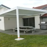 Pergola bioclimatique blanche autoportée sur une terrasse de jardin