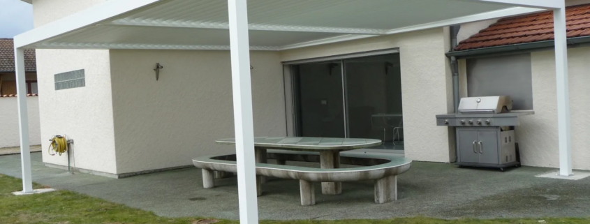 Pergola bioclimatique blanche autoportée sur une terrasse de jardin