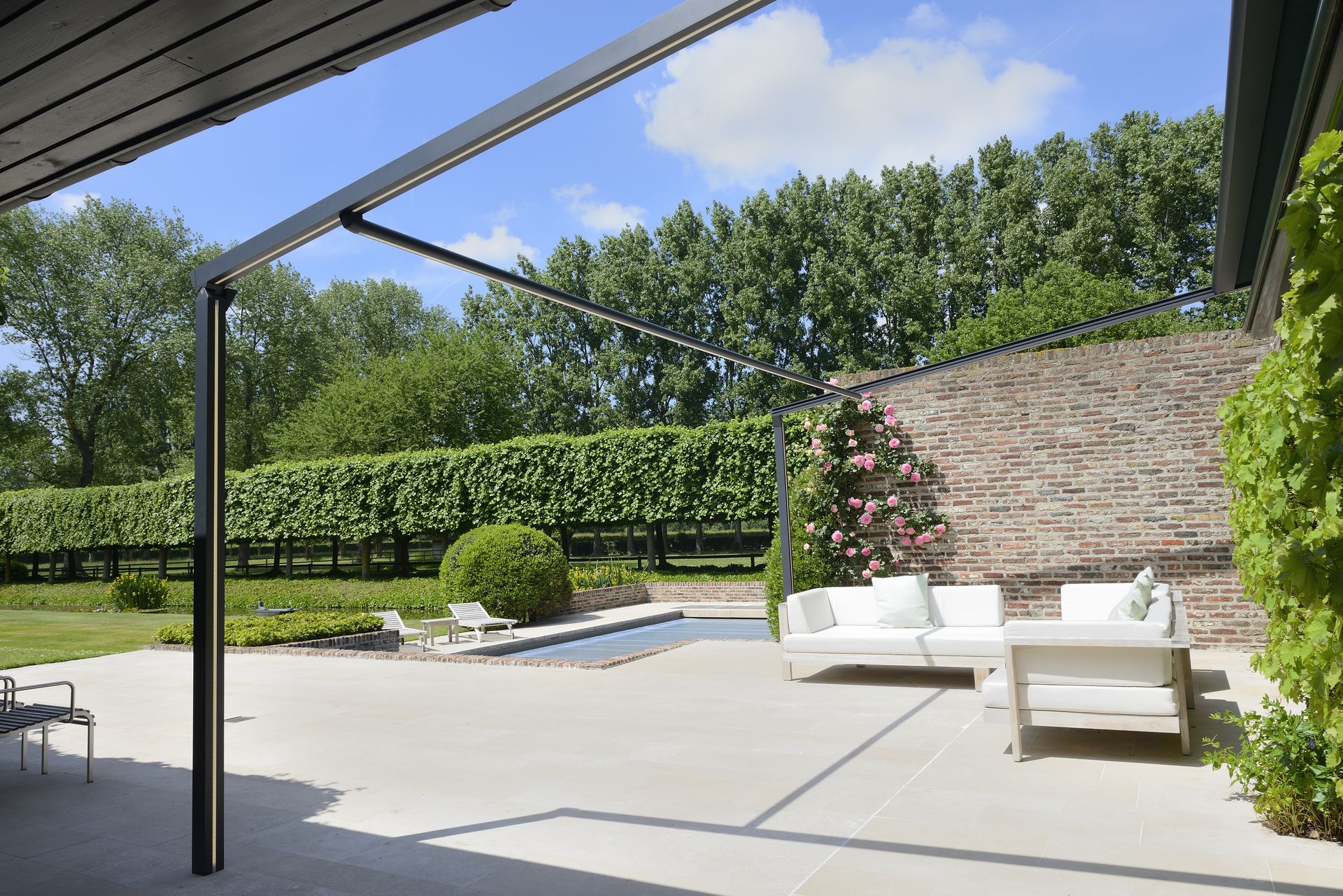 Pergola à toile Brustor B128 au-dessus d'un salon de jardin près d'un bassin