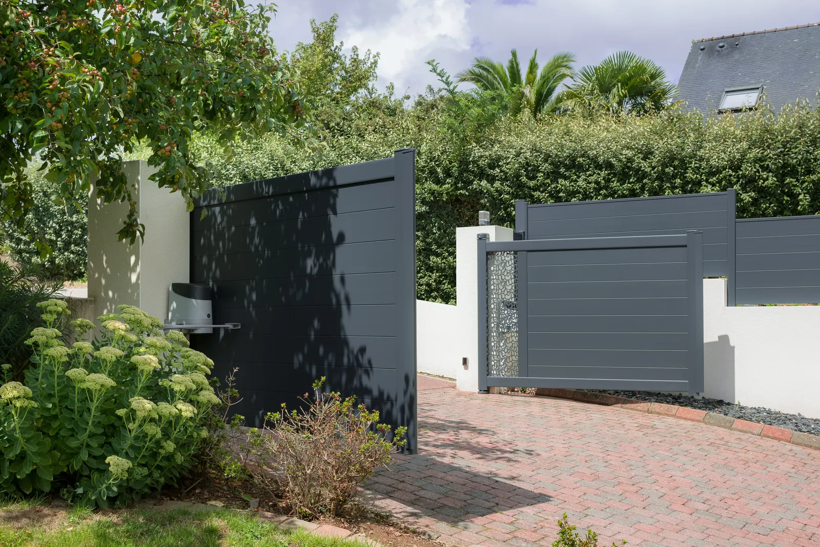 Portail battant aluminium à décor découpé au laser vu depuis le jardin