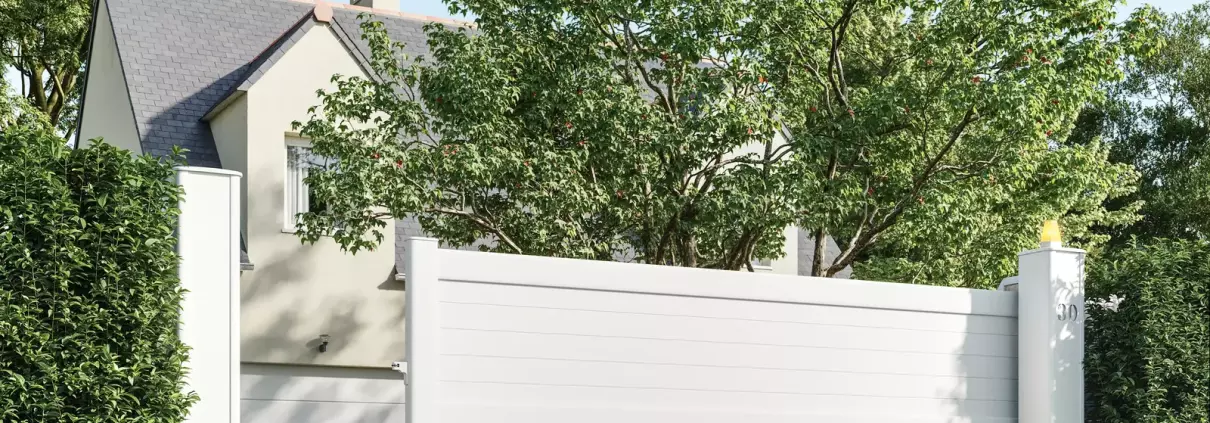 Portail coulissant aluminium blanc à décor découpé au laser devant une maison contemporaine