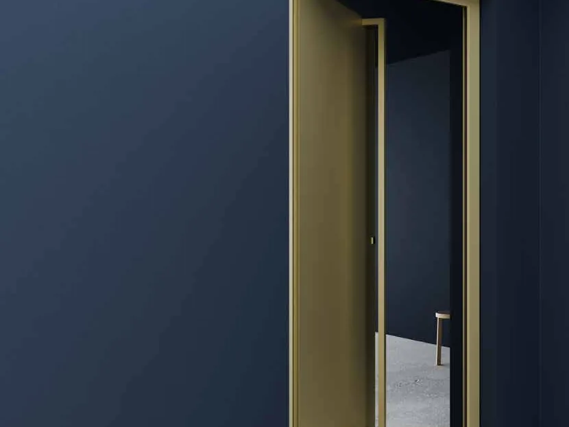 Porte d’entrée Finstral FIN-Door dorée dans un mur bleu nuit