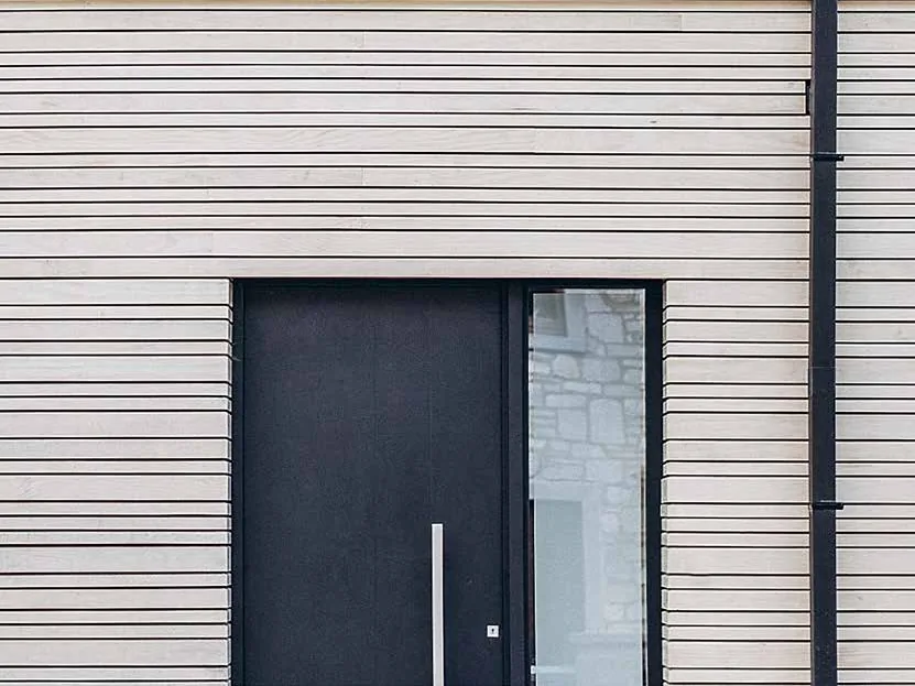 Porte d’entrée Finstral FIN-Door noire sur une maison à bardage bois clair