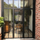 Porte-fenêtre style atelier à cadre noir ouvrant sur une pièce à vivre