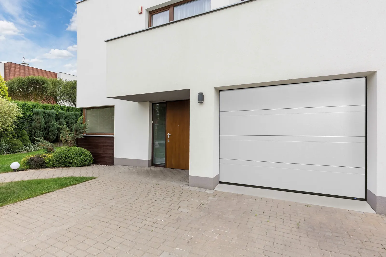 Porte de garage sectionnelle blanche sur maison contemporaine