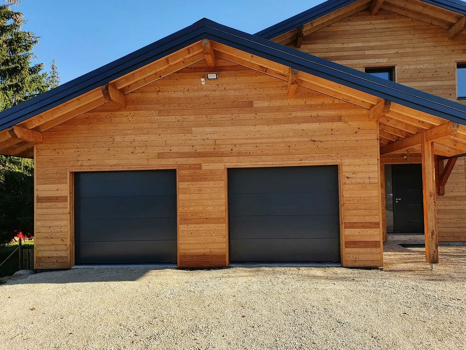 Deux portes de garage sectionnelles lisses anthracite sur maison bois