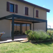 Préau en aluminium anthracite adossé à une maison, au-dessus de la terrasse