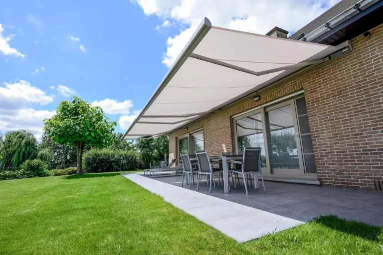 Store banne Brustor B25 déployé au-dessus d'une terrasse sur une façade en brique