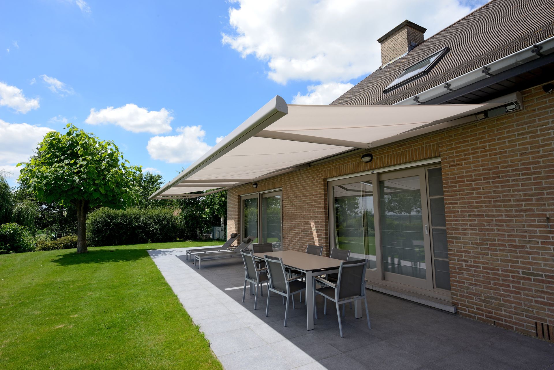 Store banne Brustor B25 vue large sur une maison en brique avec jardin