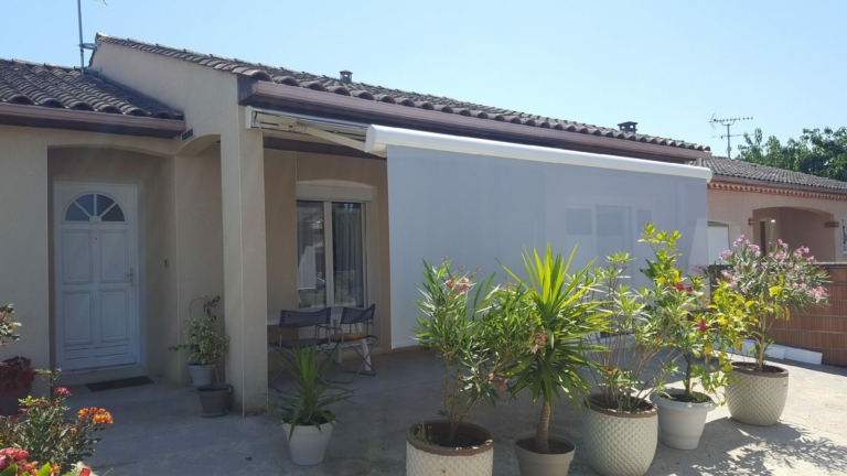 Store banne au-dessus d'une terrasse fleurie