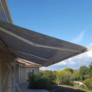 Store banne à toile grise déployé au-dessus d’une terrasse