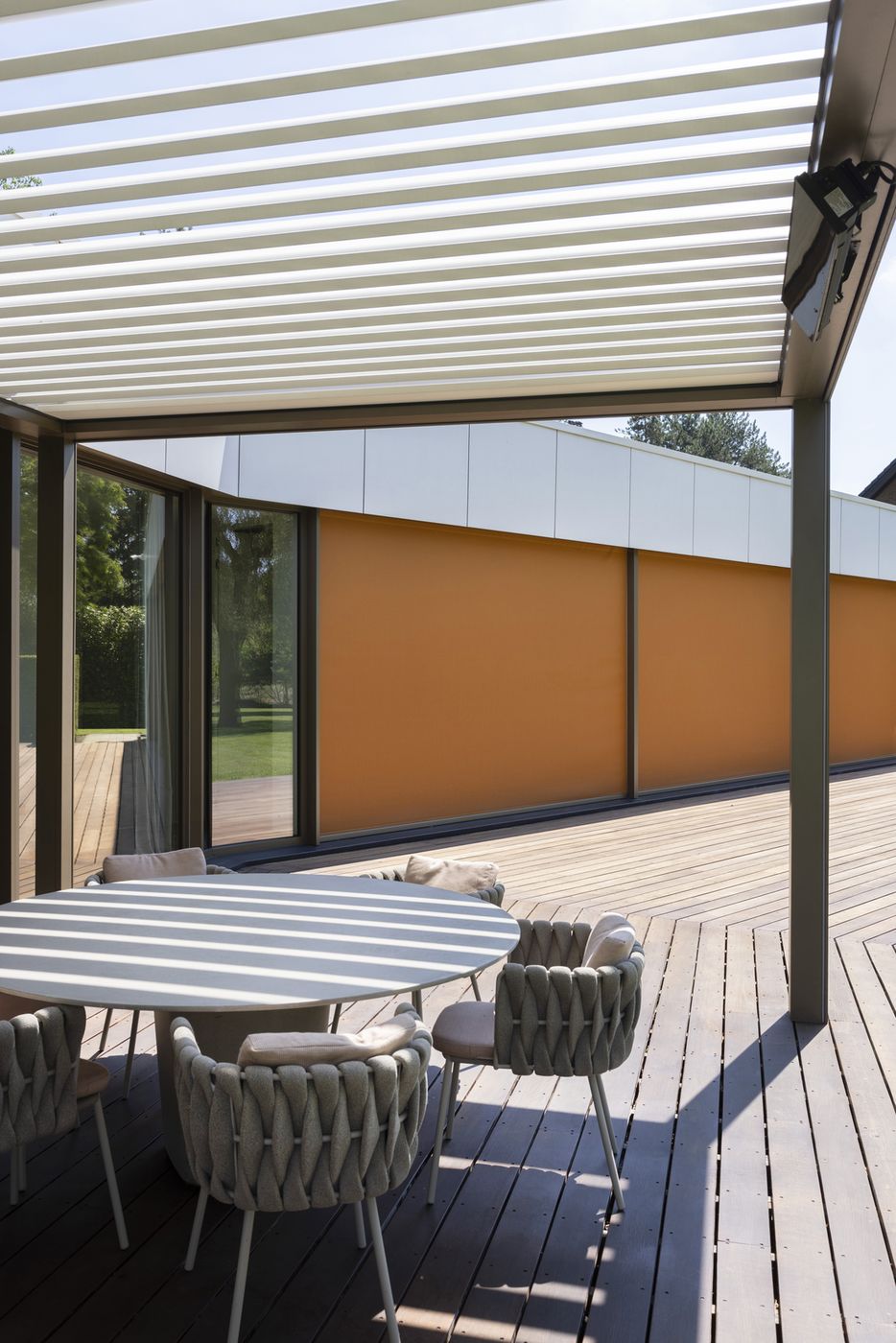 Screens ZIP Brustor orange baissés le long d'une terrasse couverte par une pergola