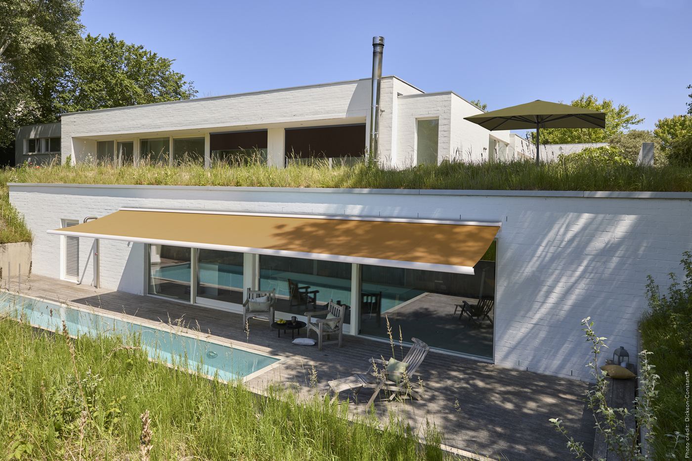 Store banne à toile Dickson ocre sur une maison contemporaine avec piscine