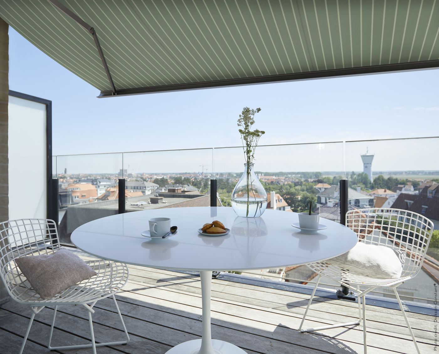 Store banne à toile Dickson verte au-dessus d'une terrasse avec vue sur la ville